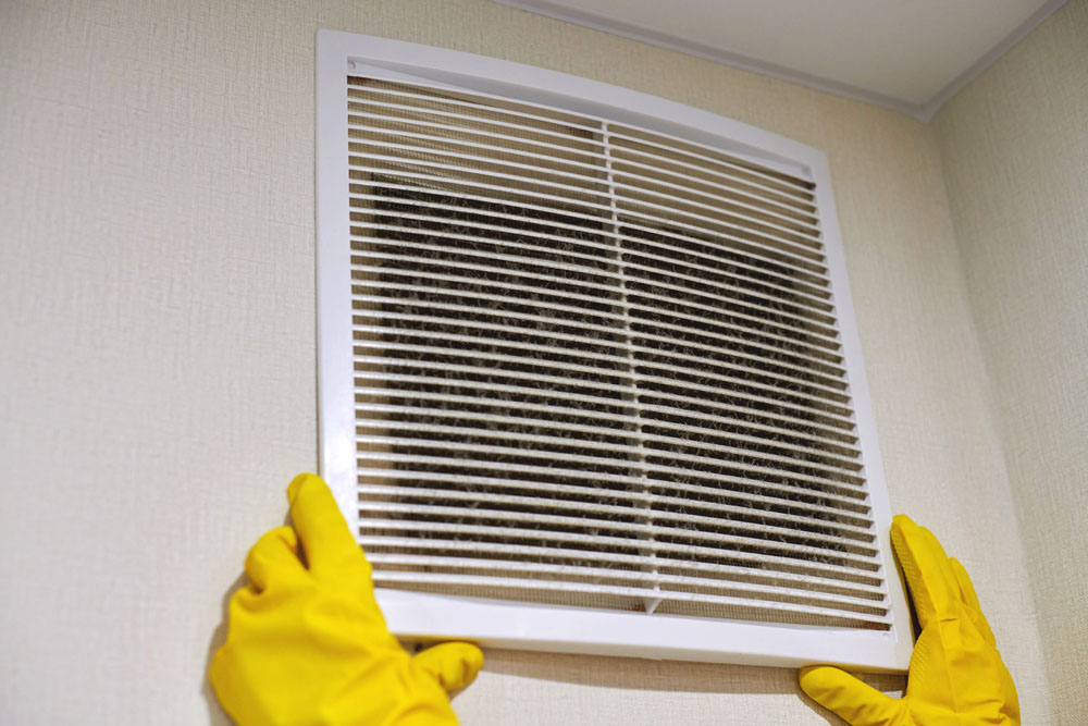 Gloved worker removing a dirty ventilation cover